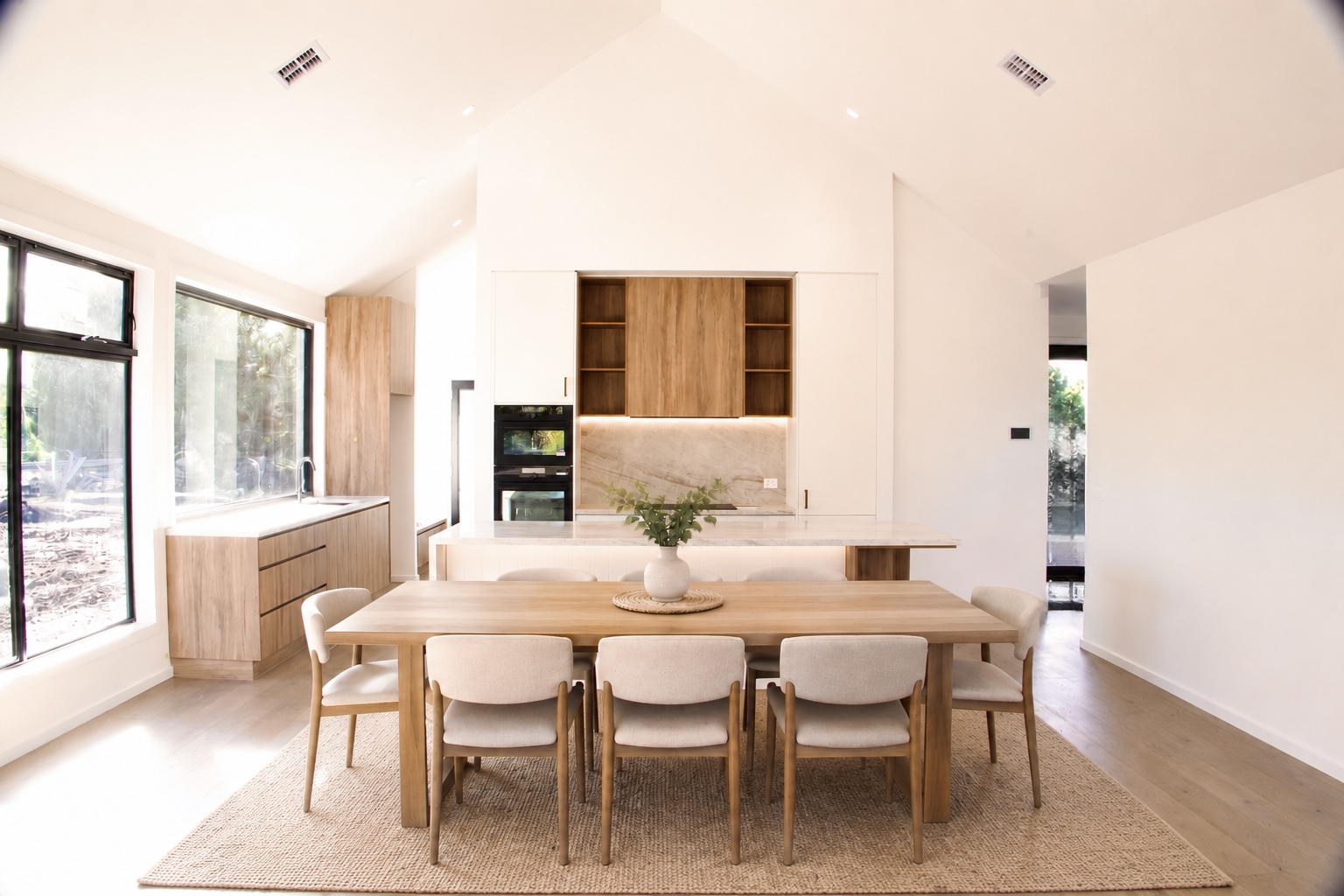 Completed open-plan kitchen and dining area with custom timber joinery and marble splashback